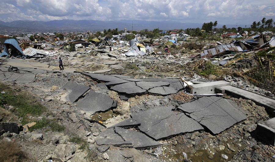 In this Oct. 6, 2018, photo, an asphalt road and toppled houses scatter across an area hit by liquefaction during an earthquake in the Balaroa neighborhood in Palu, Central Sulawesi, Indonesia. (AP Photo/Aaron Favila)