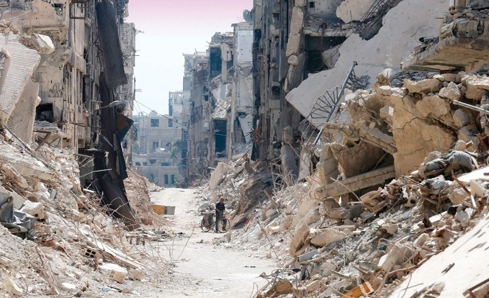 A man stands in the rubble as the Syrian regime begins to clear the wreckage at the Yarmuk Palestinian refugee camp in Damascus on Tuesday. (AFP )