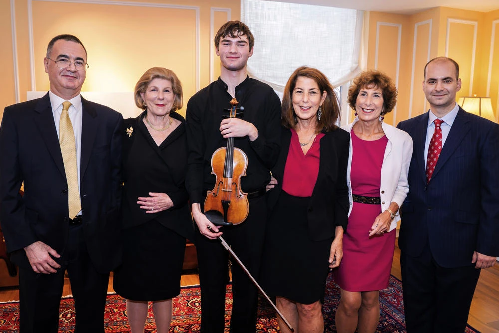 In this photo provided by Chris Lee, Juilliard student Nathan Meltzer, center, poses with the "Ames, Totenberg" Stradivari of 1734 violin loaned to him by the daughters of the late violinist Roman Totenberg, on Oct. 9, 2018 in New York. From left are Bruno Price, of Rare Violins of New York, Nina Totenberg, Meltzer, Amy Totenberg, Jill Totenberg and Ziv Arazi or Rare Violins of New York. (Chris Lee via AP)