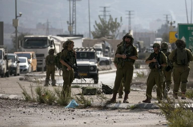 Israeli soldiers control cars at the Hawara checkpoint south of Nablus after according to the army, an Israeli reserve soldier was wounded in a stabbing attack, on October 11, 2018. (AFP)