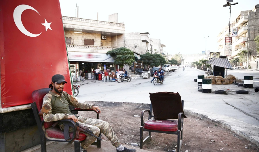 A Syrian fighter sits at the newly renamed Salahuddin Ayyubi circle in Afrin whose residents say they are suffering a litany of rights violations at the hands of Turkey-backed rebels. (AFP)