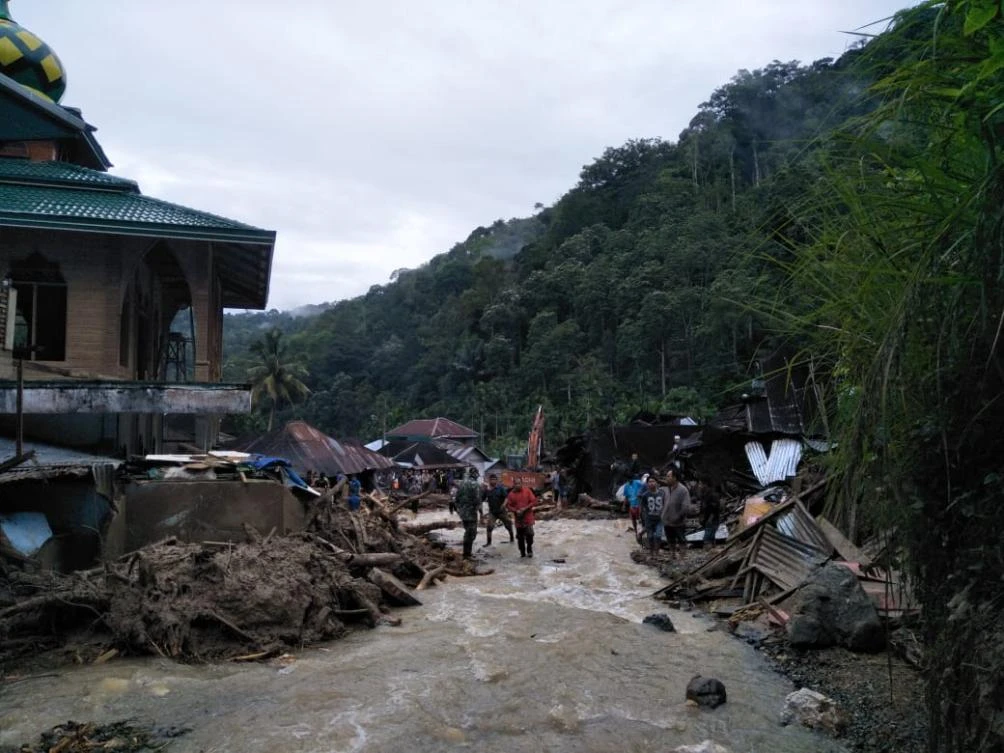 Villagers wade through flood water at the Saladi village in Mandailing Natal, North Sumatra. (AFP)