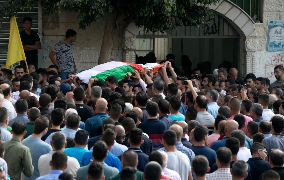 Palestinian carry the body of 48-year-old mother of eight, Aisha Rabi, who died of her wounds after the car she was traveling in with her husband was hit by stones, during her funeral in the West Bank village of Bidya, near Salfit, on October 13, 2018. (AFP)