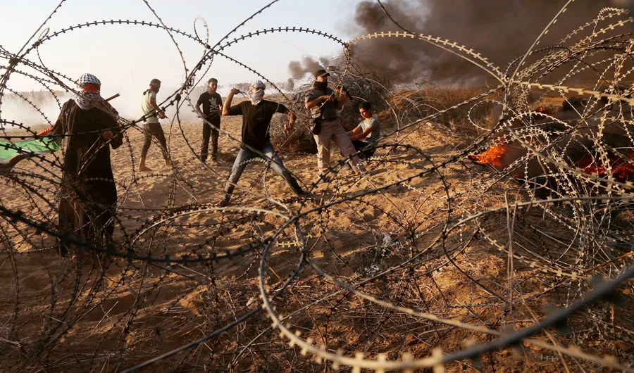 Palestinians hurl stones at Israeli troops during a protest calling for lifting the Israeli blockade on Gaza and demanding the right to return to their homeland, at the Israel-Gaza border fence in the southern Gaza Strip Oct. 12, 2018. (REUTERS)