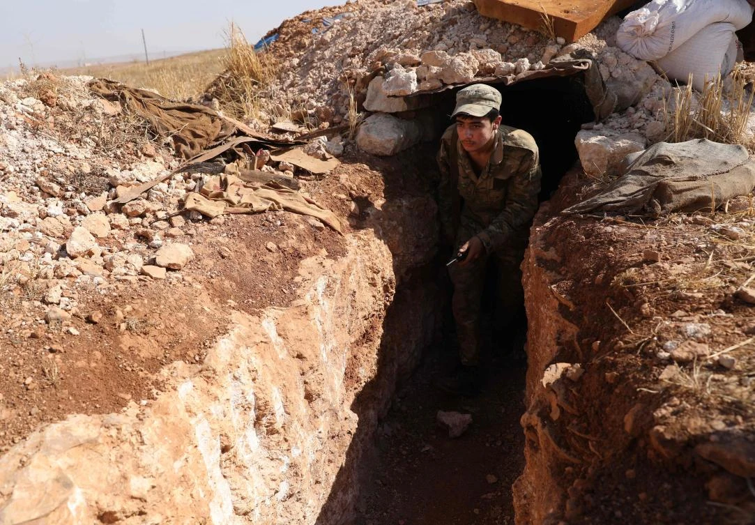 A Syrian rebel-fighter from the National Liberation Front (NLF) walks through a trench at the frontline facing regime areas in the southern countryside of Aleppo on October 14, 2018. (AFP)