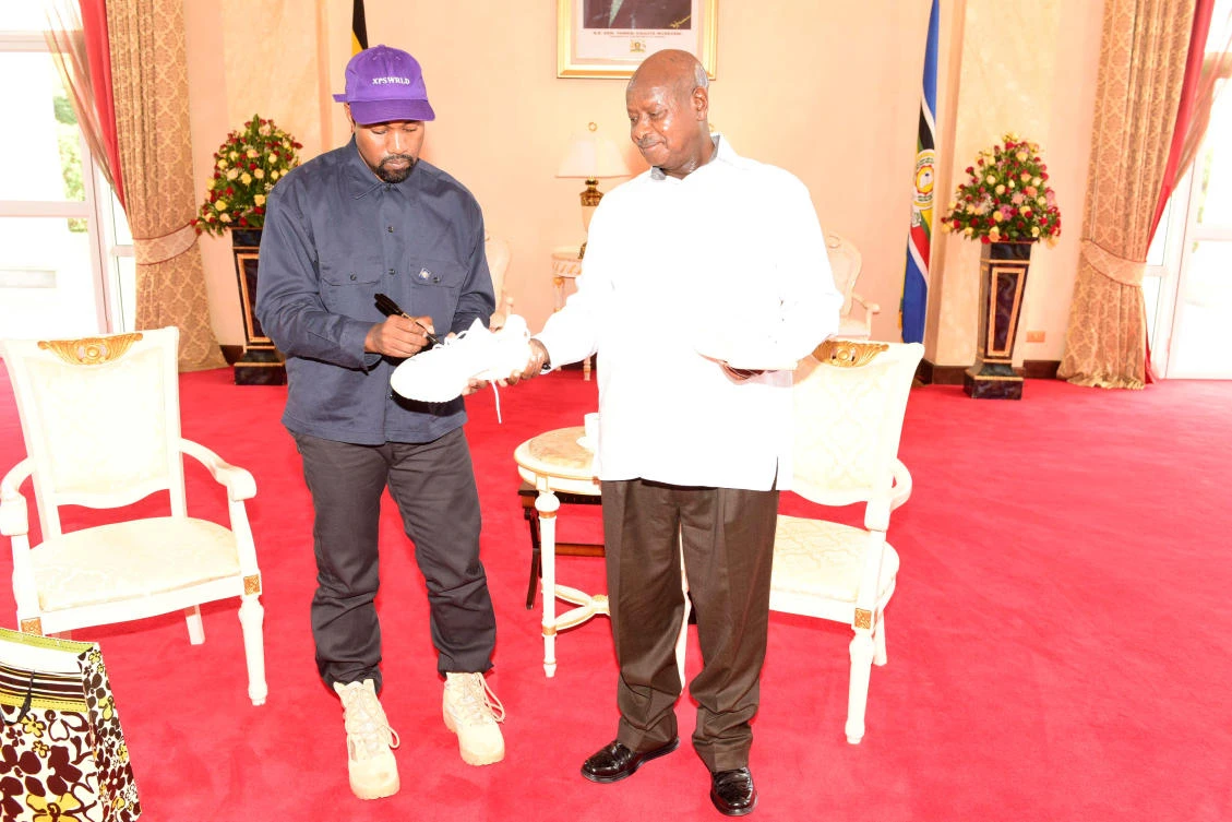 Rapper Kanye West (L) autographs a shoe as he meets Uganda's President Yoweri Museveni when he paid a courtesy call at State House, Entebbe, Uganda October 15, 2018. (Reuters)