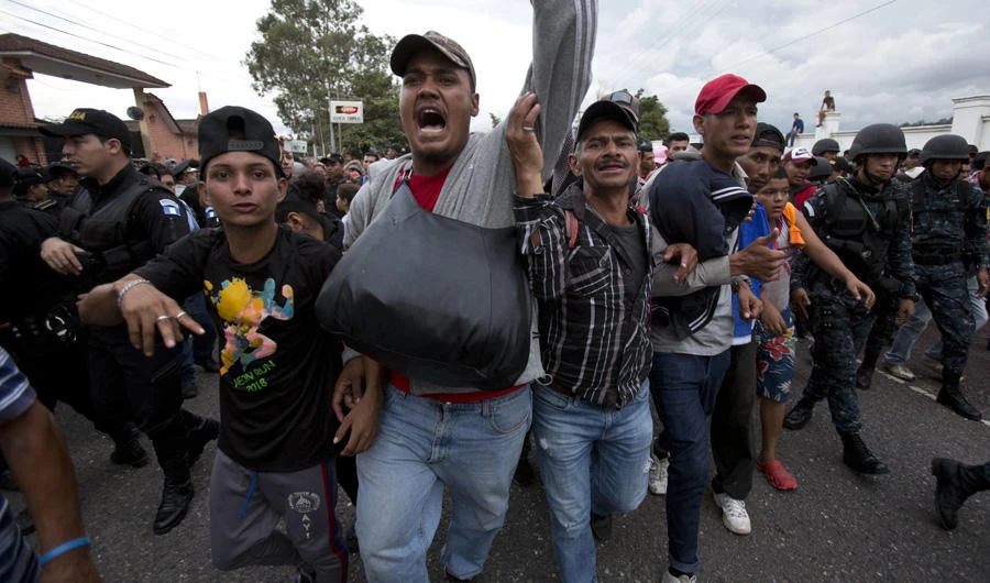 Honduran migrants walk past a roadblock of Guatemalan police as they make their way to the US, in Esquipulas, Guatemala, on Oct. 15, 2018. Police stopped the migrants for several hours but the travelers refused to return to the border and were eventually allowed to pass. (AP Photo/Moises Castillo)
