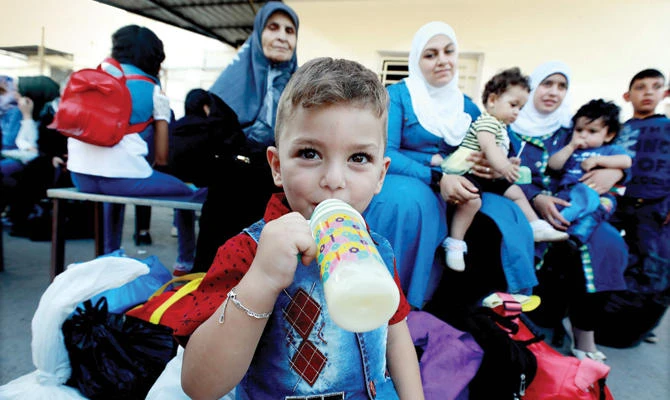 Syrian child Luay drinks milk before boarding a bus with his family on Sept. 17, as they return to Syria after living as refugees in Lebanon for years. (AFP)