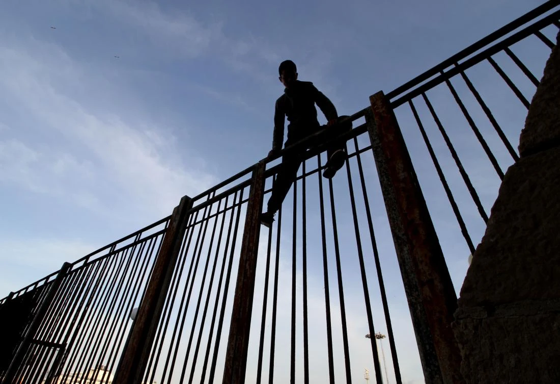 In this file photo taken on May 16, 2017 a Moroccan youngster climbs a fence in the port of the Spanish enclave of Melilla bordering Morocco. (AFP)
