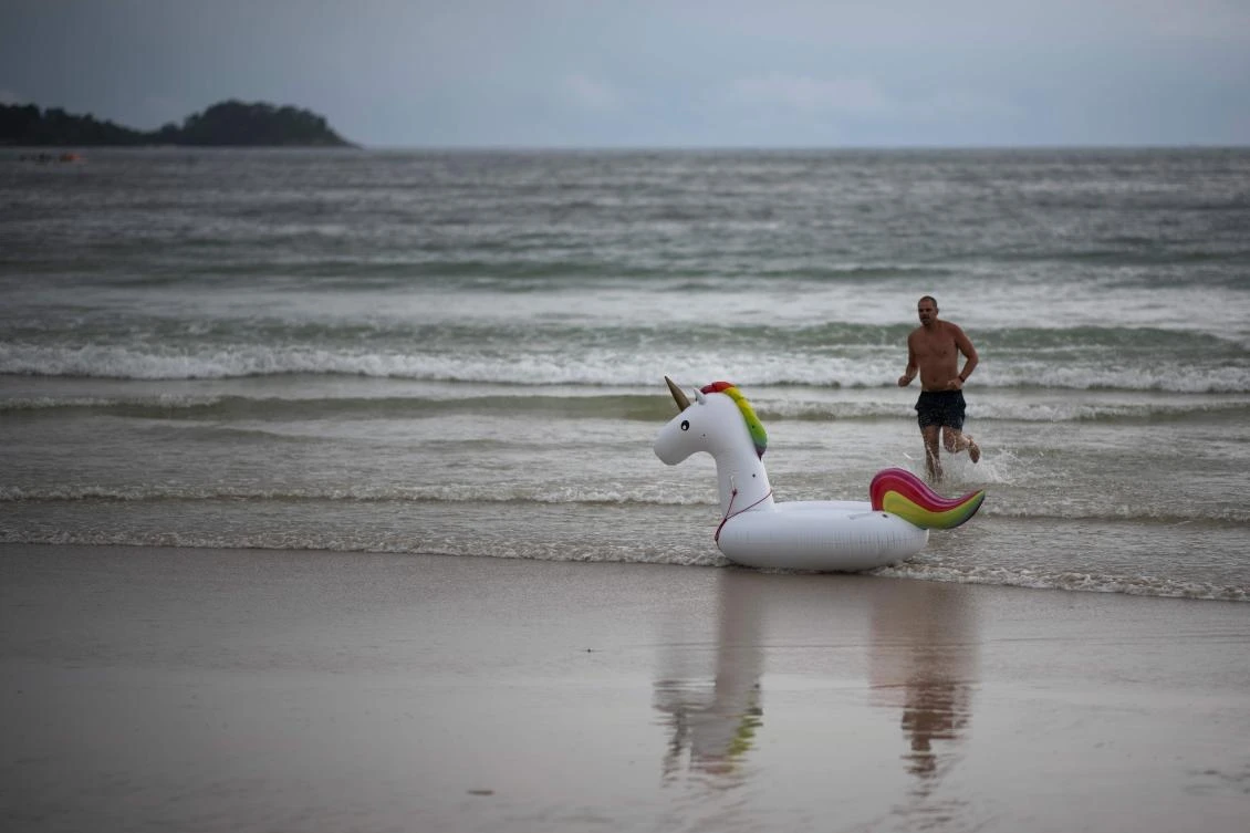 A tourist runs after his lose unicorn-floaty at the Patong Beach in Phuket on October 12, 2018. (AFP)
