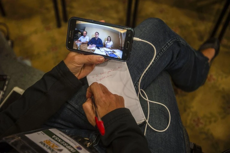 Facebook closed 68 pages and 43 accounts that media reported was promoting Social Liberal Party presidential candidate Jair Bolsonaro, above on screen, online on a massive scale. (AFP)