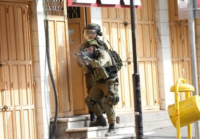 Israeli soldiers stand and take aim during clashes with Palestinian protesters following a demonstration on Friday, October 19 in the occupied West Bank city of Hebron. (AFP)