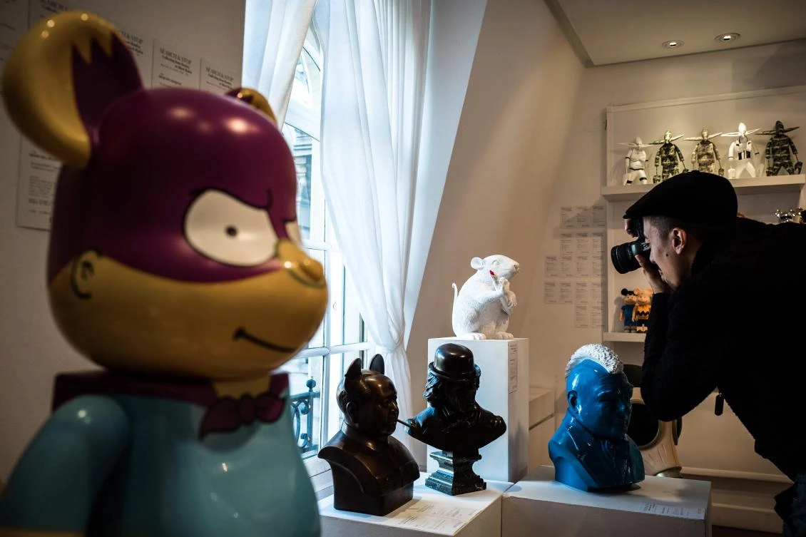 A man takes a picture of an artworks by street artist Banksy prior to an Artcurial French auction house sale at in Paris. (AFP)