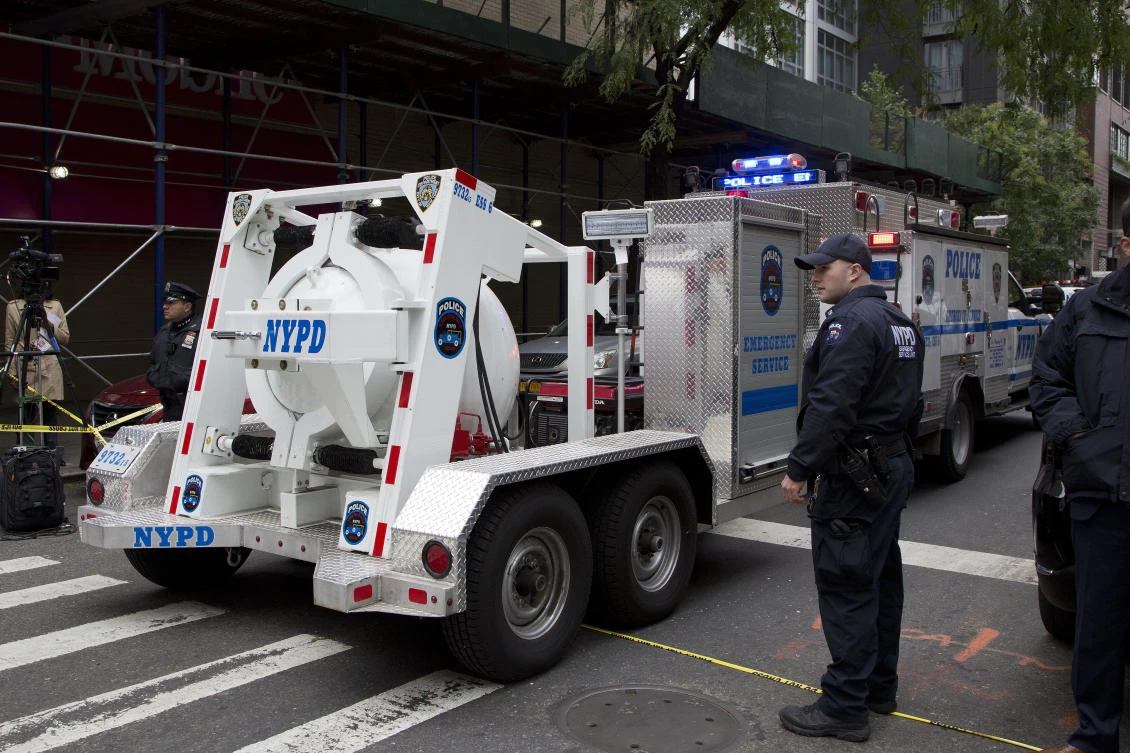 A police truck tows a total containment vessel to a post office in midtown Manhattan to dispose of a suspicious package. (AP Photo)