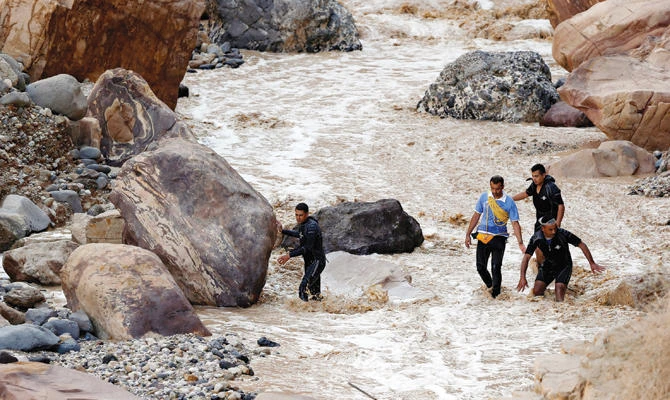 Civil defense members work to find survivors after rain storms unleashed flash floods near the Dead Sea in Jordan on Friday. Inset top: The Jordanian flag flies half-mast as a mark of respect for those killed. (Reuters)
