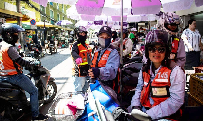 This photo taken on September 26, 2018 shows three female motorcycle-taxi drivers waiting at a motorcycle-taxi stand in Bangkok. (AFP)