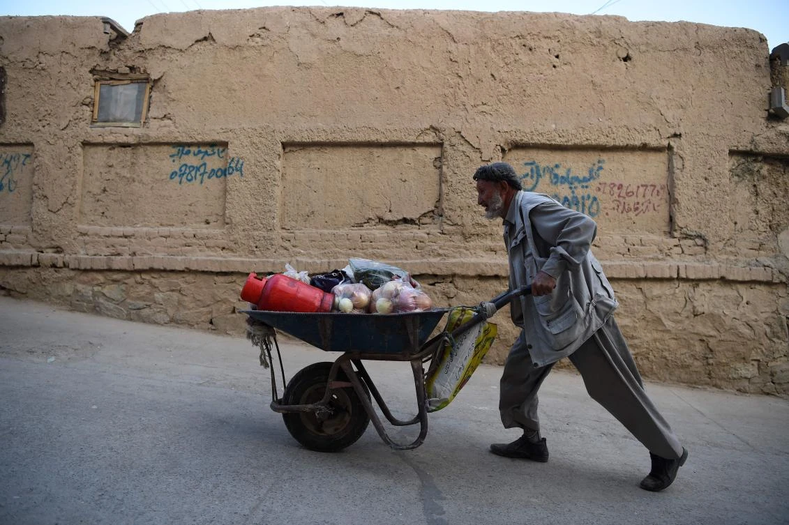 An Afghan labourer pushes his wheelbarrow loaded with groceries in Kabul on October 25, 2018. / AFP / WAKIL KOHSAR