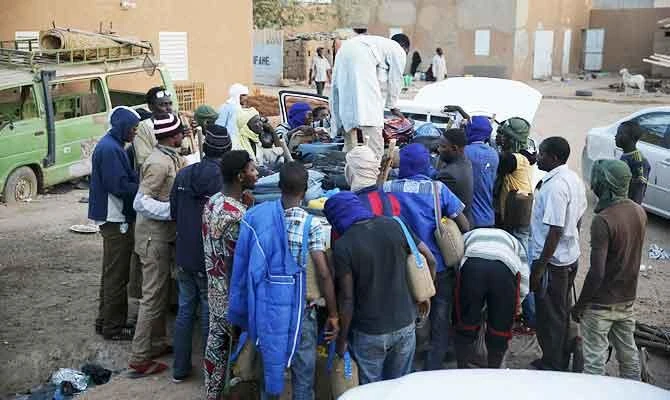 Migrants watch as a man arranges their belongings in the back of a truck at a local immigration transit centre in the desert town of Agadez, Niger, in this May 25, 2015 file photo. (REUTERS)