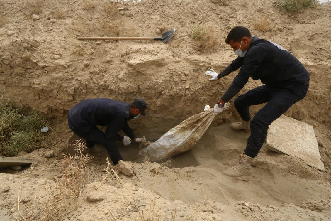Workers pull an unidentified body at a mass grave in Raqqa, Syria. (Reuters)