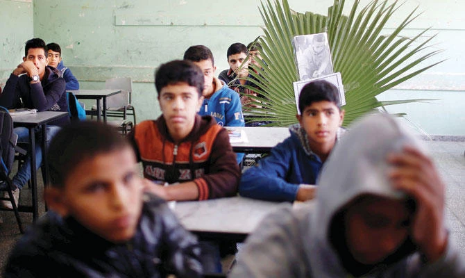 A picture of Khaled Saed, a 14-year-old Palestinian boy who was killed with other two boys in an Israeli air strike, is seen on his chair as his classmates react at a school in the central Gaza Strip Monday. (Reuters)