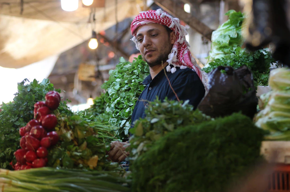 A market trader sells vegetables at his stall in downtown Amman. Jordan needs more support for small businesses, a conference in London heard on Wednesday. (AFP)