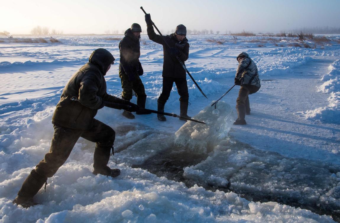 Villagers harvest ice from a local lake near the settlement of Oy, some 70 km south of Yakutsk, with the air temperature at about minus 41 degrees Celsius, on November 27, 2018. Many people in the Sakha (Yakutia) Republic depend on melted water as there is no other way to supply water due to extremely cold winter temperatures in the permafrost-covered region. / AFP / Mladen ANTONOV