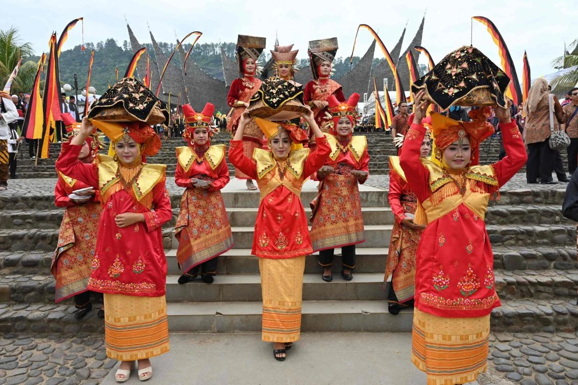 Indonesian students in Minangkabau traditional outfits welcome guests at the 2018 Minangkabau art and culture festival in Batusangkar, West Sumatra with the Istano Basa Pagaruyuang at the background on November 28, 2018. The 2018 Minangkabau art and culture festival featuring variety of Minangkabau - one of Indonesia's ethnics - arts and culture that is held in Tanah Datar regency from November 28 - December 2 to boost both economy and tourism. / AFP / ADEK BERRY