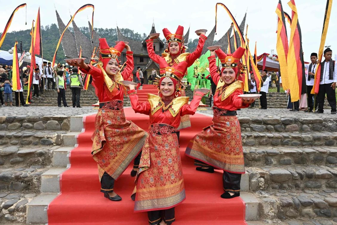 Indonesian dancers pose for photographers during the 2018 Minangkabau art and culture festival in Batusangkar, West Sumatra with the Istano Basa Pagaruyuang at the background on November 28, 2018. The 2018 Minangkabau art and culture festival featuring variety of Minangkabau - one of Indonesia's ethnics - arts and culture that is held in Tanah Datar regency from November 28 - December 2 to boost both economy and tourism. / AFP / ADEK BERRY