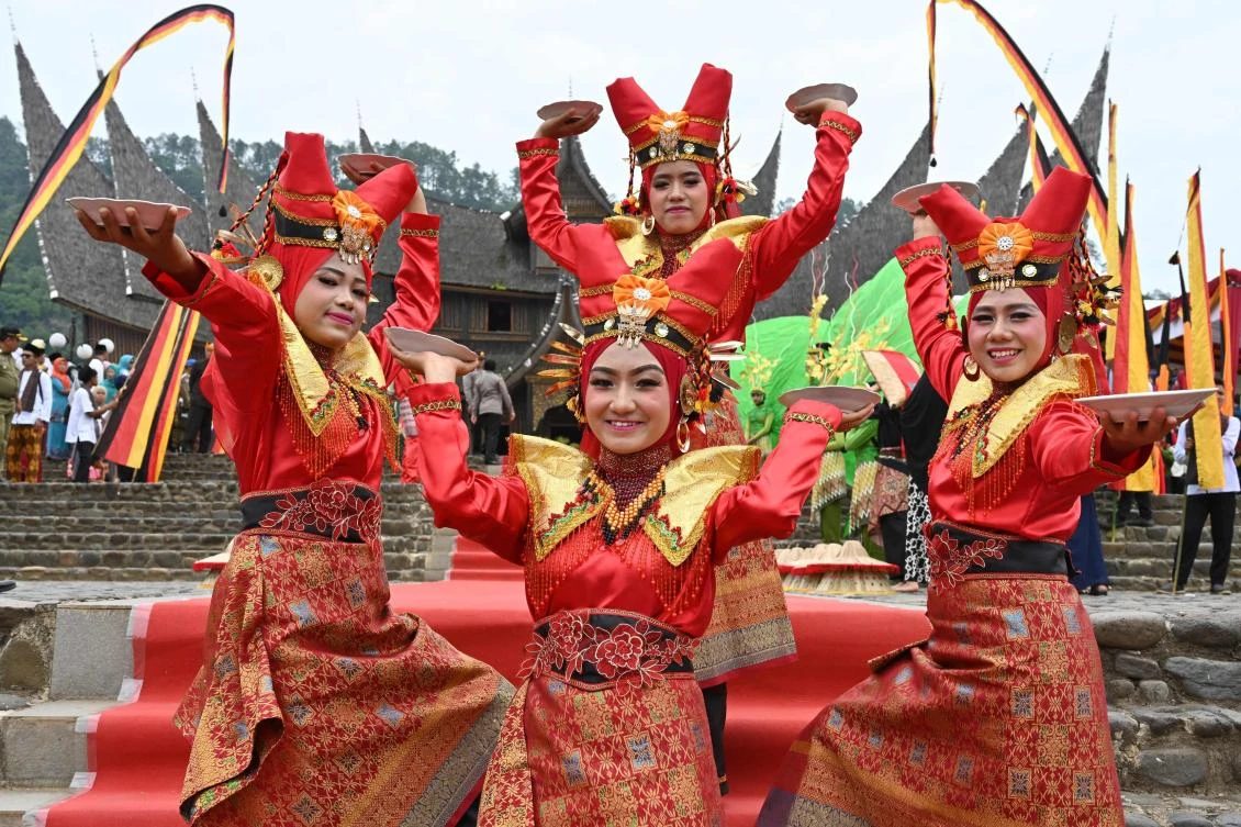 Indonesian dancers pose for photographers during the 2018 Minangkabau art and culture festival in Batusangkar, West Sumatra with the Istano Basa Pagaruyuang at the background on November 28, 2018. The 2018 Minangkabau art and culture festival featuring variety of Minangkabau - one of Indonesia's ethnics - arts and culture that is held in Tanah Datar regency from November 28 - December 2 to boost both economy and tourism. / AFP / ADEK BERRY