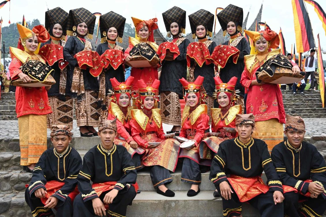 Indonesian dancers pose for photographers during the 2018 Minangkabau art and culture festival in Batusangkar, West Sumatra with the Istano Basa Pagaruyuang at the background on November 28, 2018. The 2018 Minangkabau art and culture festival featuring variety of Minangkabau - one of Indonesia's ethnics - arts and culture that is held in Tanah Datar regency from November 28 - December 2 to boost both economy and tourism. / AFP / ADEK BERRY