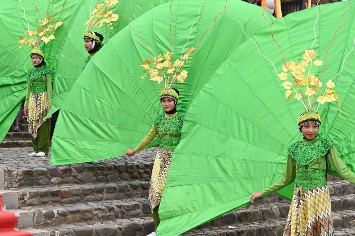 Indonesian dancers stand prior to their performing during the 2018 Minangkabau art and culture festival in Batusangkar, West Sumatra with the Istano Basa Pagaruyuang at the background on November 28, 2018. The 2018 Minangkabau art and culture festival featuring variety of Minangkabau - one of Indonesia's ethnics - arts and culture that is held in Tanah Datar regency from November 28 - December 2 to boost both economy and tourism. / AFP / ADEK BERRY