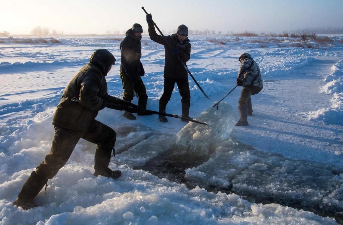 Villagers harvest ice from a local lake near the settlement of Oy, some 70 km south of Yakutsk, with the air temperature at about minus 41 degrees Celsius, on November 27, 2018. Many people in the Sakha (Yakutia) Republic depend on melted water as there is no other way to supply water due to extremely cold winter temperatures in the permafrost-covered region. / AFP / Mladen ANTONOV