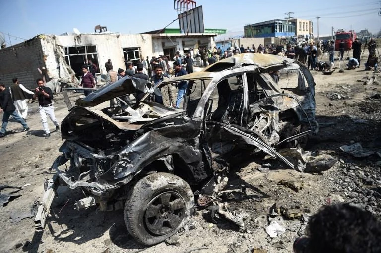 Afghan security personnel and civilians gather next to a damaged car at the site of a Taliban car bomb attack in Kabul on March 17, 2018. (AFP)