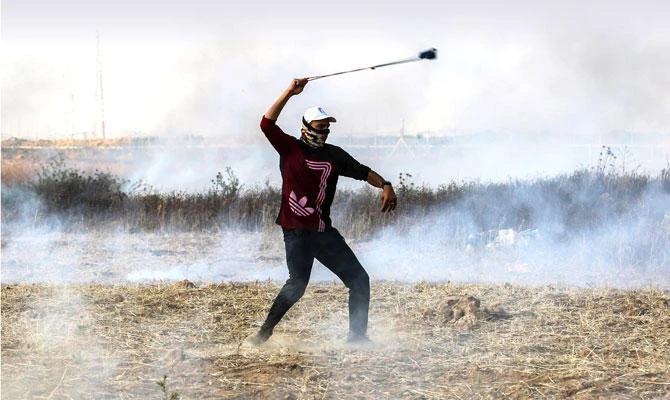 A Palestinian protester uses a slingshot to throw a stone toward Israeli forces during clashes in Gaza strip. (AFP/file photo)