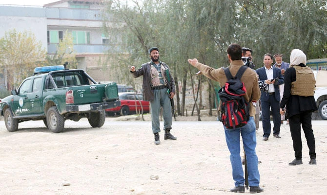 A policeman prevents journalists from walking near the site of a suicide attack on prison employees' vehicle in Kabul, Afghanistan, Oct. 31, 2018. (AP)