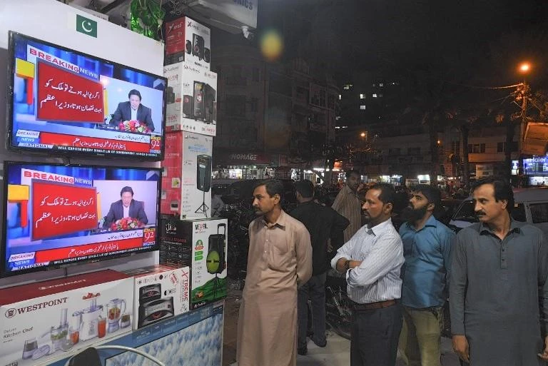 Residents watch Pakistani Prime Minister Imran’s televised address after his visit to Saudi Arabia last month, where he received a $6 billion rescue package. (AFP)