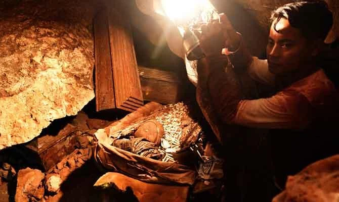 This photo taken on September 11, 2018 shows a guide holding a light over the remains of bodies interned in a burial cave in Londa in Tana Toraja regency. (AFP)