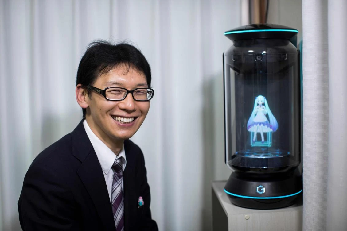 Akihiko Kondo poses next to a hologram of virtual reality singer Hatsune Miku at his apartment in Tokyo, a week after marrying her. (AFP)