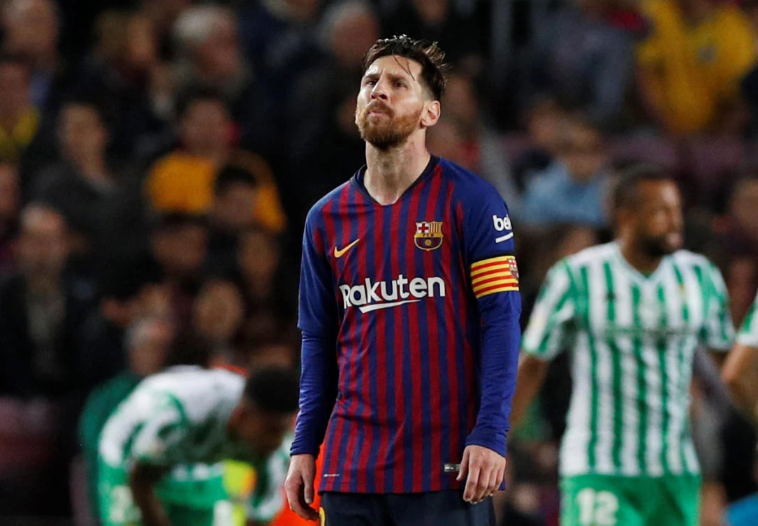 Barcelona's Lionel Messi looks dejected as Real Betis' Sergio Canales celebrates scoring their fourth goal with team mates. (Reuters)