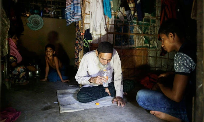In this photograph taken Aug. 24, 2018, Rohingya Rohingya faith healer Abul Kalam, left, whispers prayers into a water bottle for his patient, in Kutupalong refugee camp, Bangladesh. (AP)