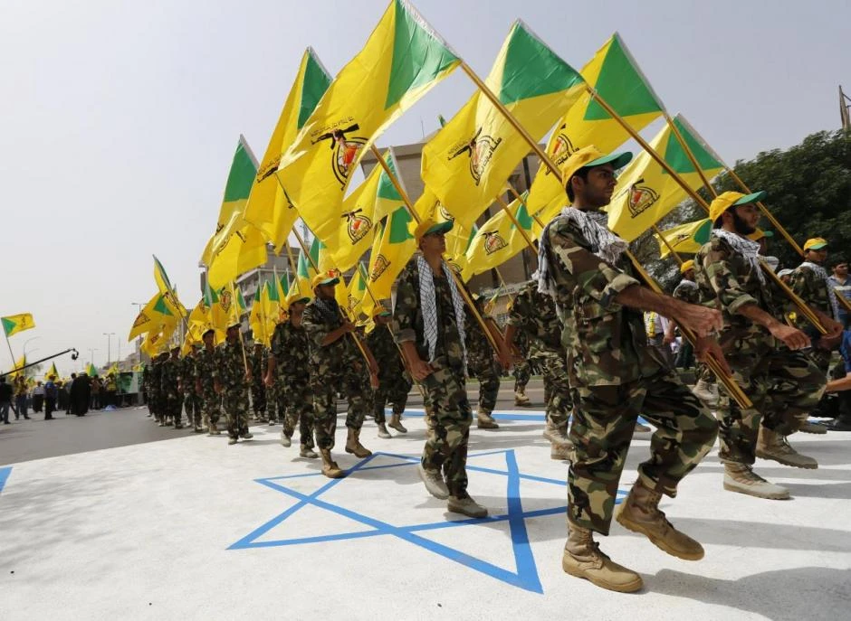 Iraqi Shi'ite Muslim men from the Iranian-backed militia Kataib Hezbollah hold the party's flags as they walk along a street. (File photo: Reuters)