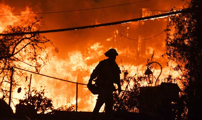 A firefighter is silhouetted by a burning home along Pacific Coast Highway (Highway 1) during the Woolsey Fire on November 9, 2018 in Malibu, California. (AFP)