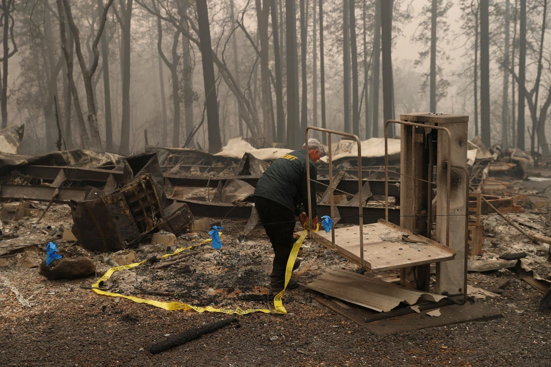 A Butte County Sheriff deputy places yellow tape at the scene where human remains were found during the Camp fire in Paradise, California. (Reuters)