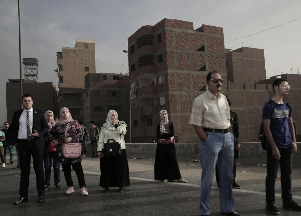 People wait for an early morning bus on the ring road, in Cairo, which may soon witness an exodus by some of its well-heeled residents, state employees and foreign embassies to a new capital. (AP)