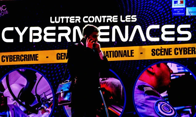 In this file photo taken on January 23, 2018 a person walks past a poster reading "fight against cyber threats" during the 10th International Cybersecurity Forum in Lille. (AFP)