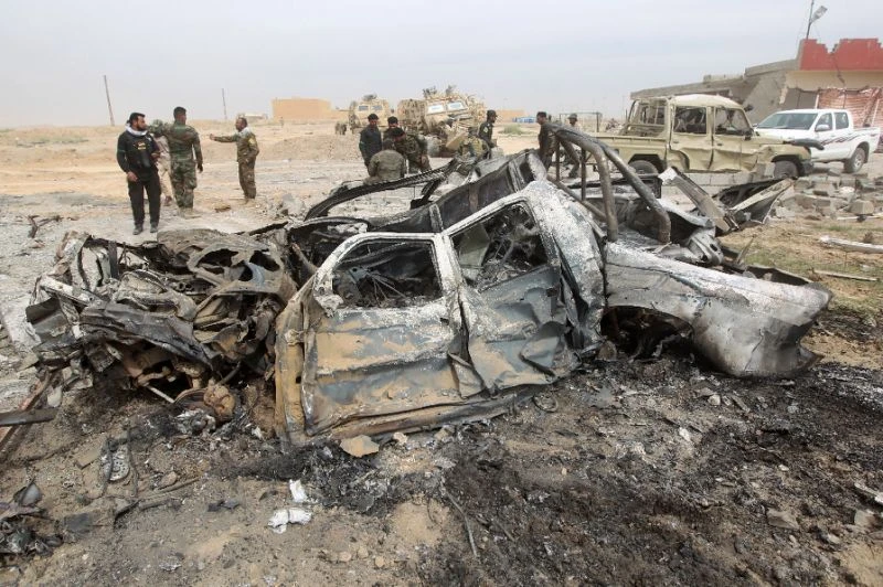 In the file photo, Iraqi Shiite fighters stand at the site of a car bomb in 2015 in a suburb of Tikrit. A car bomb blast killed at least five people and wounded 16 others in the city on Sunday. (AFP/File Photo)