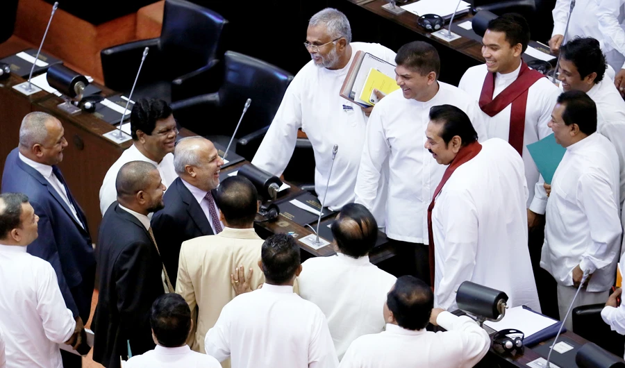 Sri Lanka's newly appointed Prime Minister Rajapaksa speaks to Sri Lanka Muslim Congress leader Hakeem and All Ceylon Makkal Congress leader Bathiudeen before they leave the parliament in Colombo. (Reuters)