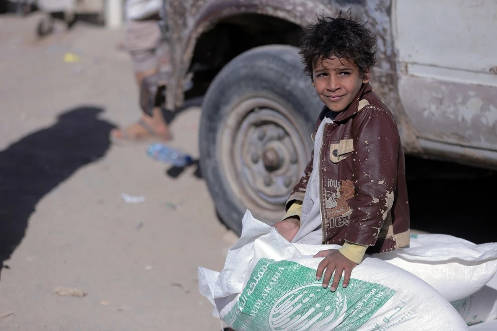 A displaced Yemeni child sits on sacks of Saudi-provided humanitarian food aid at a camp in Yemen's northeastern province of Marib on January 26, 2018. (File/AFP)