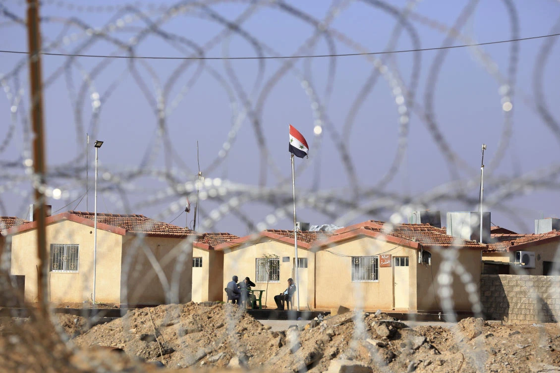 Iraqi troops and Shiite militiamen outside Qaim keep watch over a giant earth barricade topped with barbed wire. (AP)