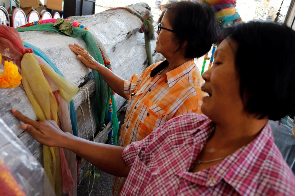 Thai women rub an ancient bark tree, as they look for lottery lucky numbers at Wat Kunnatri Ruttharam temple in Bangkok. (Reuters)